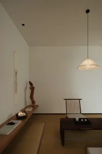 A modern minimalist living room featuring a wooden floor, low table, and pendant light.