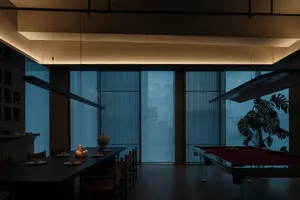 A modern minimalist living room with a black dining table, candles, and a pool table in the background.