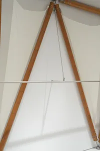 An architectural space with white cloth panels supported by wooden trusses.