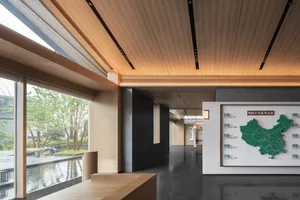 Modern office lobby with wooden features and greenery outside, focusing on a map display.