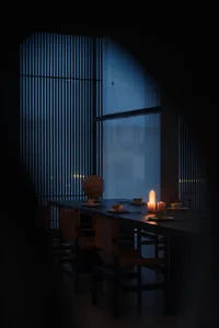 A minimalist dining room with wooden paneling and a lit candle setting the scene.