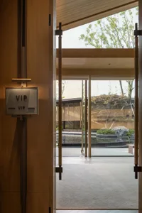 A modern hotel lobby featuring glass walls and a serene outdoor view.