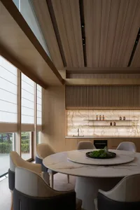 A modern kitchen and dining area featuring a marble table and floor-to-ceiling windows.