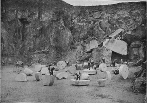 Workers at a construction site with large stone blocks and rocks.