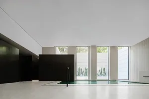 An industrial-style pool enclosed by concrete walls and large windows, featuring a minimalist design with a modern aesthetic.