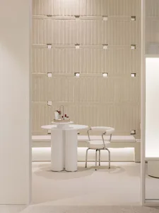 A minimalist interior space with a concrete wall and white furniture.
