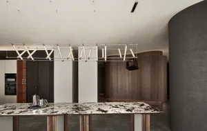 Modern minimalist dining room featuring a marble table and contemporary lighting fixture.