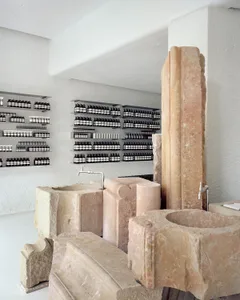 Minimalist retail storefront showcasing stone shelves and products on white shelves