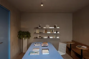 A spacious, modern bookshop featuring minimalist concrete shelving and metal accents.