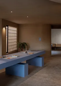 A modern living room with concrete walls, blue furniture, and a glass window.