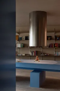 A minimalist room with a blue and metallic bookshelf, featuring a sculpture of a lion on a book.