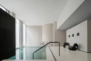 A modern indoor swimming pool with concrete flooring and minimalist design elements.