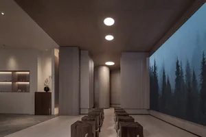 A dimly lit interior space featuring wooden columns and a large screen displaying a tranquil forest scene.