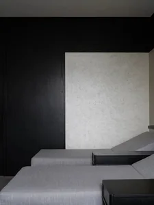 A minimalist sofa with black and white upholstery against a textured wall.