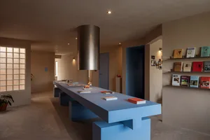 A modern library interior featuring a long concrete counter and shelves with books.