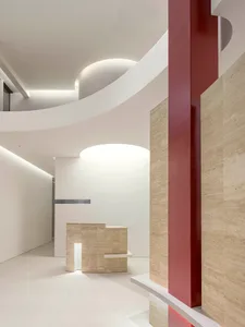 A minimalist modern office reception area with concrete flooring and curved architectural elements.