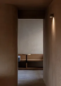 Minimalist room with wooden furniture, concrete walls, and soft lighting, designed to create a serene and modern atmosphere.