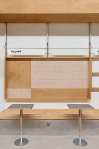 A minimalist workspace featuring wooden elements and a pegboard for supplies.