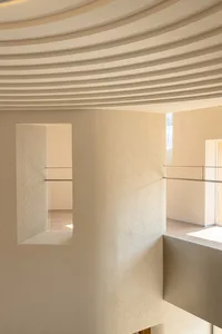 A modern interior space with concrete walls and a ribbed ceiling.