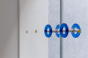 A close-up view of a modern glass door handle in blue color.