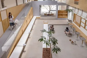 People interacting with dogs in a modern, minimalist public space with concrete flooring.