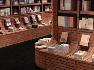 An image of a bookstore interior with bookshelves lined with books and a brick wall.