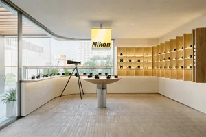 A minimalist photography exhibition featuring a wooden shelving system with cameras displayed.