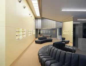 A modern retail space featuring white painted walls, steel display shelves and glass showcases for eyewear, with black leathe