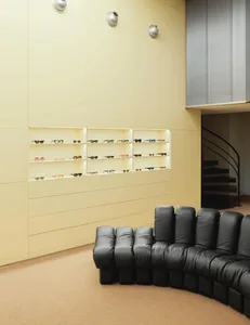 An interior display of a retail store showcasing various sunglasses in a modern glass and metal shelving unit, accompanied by