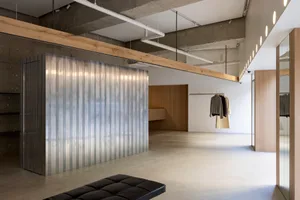 Modern minimalist clothing store with concrete, metal, and wooden elements.