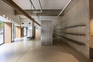 Industrial-style minimalist office interior with concrete walls, wood accents, and open space design.