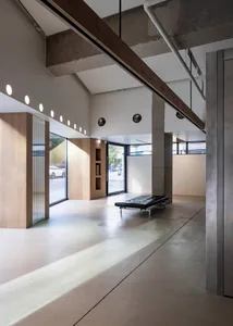Industrial-style office space with concrete walls, large windows, and minimalist furnishings.