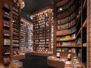 A modern library interior with curved brick walls displaying a vast collection of books.