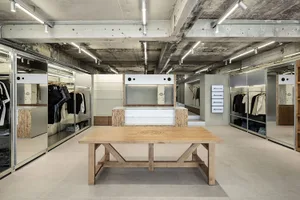 Interior of an industrial-style retail shop with wooden tables, concrete floors, and metal railings.