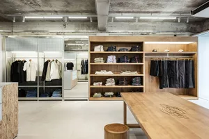 A minimalist retail space with wooden shelves and clothing racks.