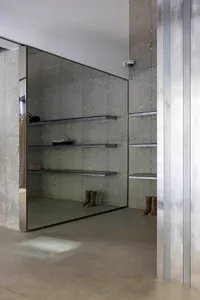 Modern concrete closet with glass doors and metal shelves