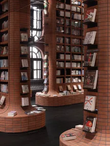 A modern library with brick walls and shelves filled with books.