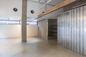 現代工業風辦公空間，混凝土牆面與地板，搭配混凝土樑與金屬板材。