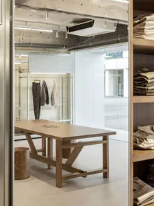 A minimalist retail space featuring a wooden counter with clothing racks and shelves.