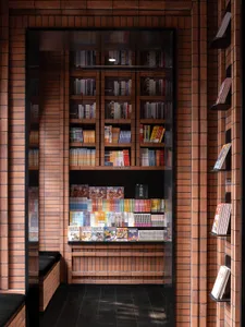 Modern library interior with brick walls, glass display cases, and numerous books on shelves.