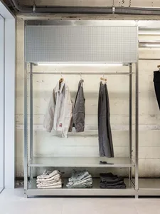 A retail store display featuring clothing items on metal racks with concrete elements.