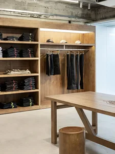 Modern retail store with wooden shelves displaying clothing items.