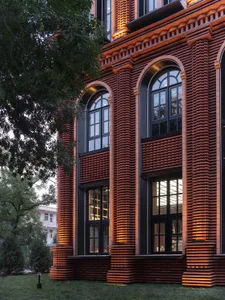 Modern building exterior featuring brick walls illuminated by warm lighting.