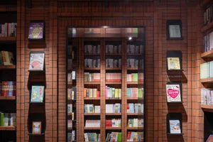 A brick wall bookstore displaying various books on shelves arranged in an organized manner.