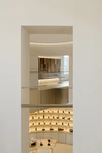 A modern photography exhibition space featuring glass shelving units and a concrete floor.