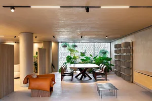 Modern cafe interior with concrete and natural materials, featuring industrial-style furniture and greenery.