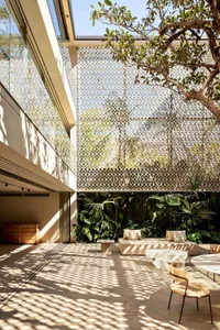 A modern garden pavilion featuring glass walls and a covered seating area with plants.