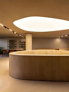 A modern retail store with a circular wooden counter and a large, illuminated oval ceiling light.