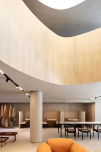 A minimalist restaurant interior with wooden seating, concrete walls, and metal accents.