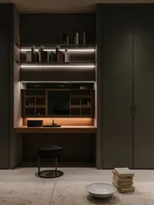 A modern home office with a wooden desk, glass shelves, and leather seating.